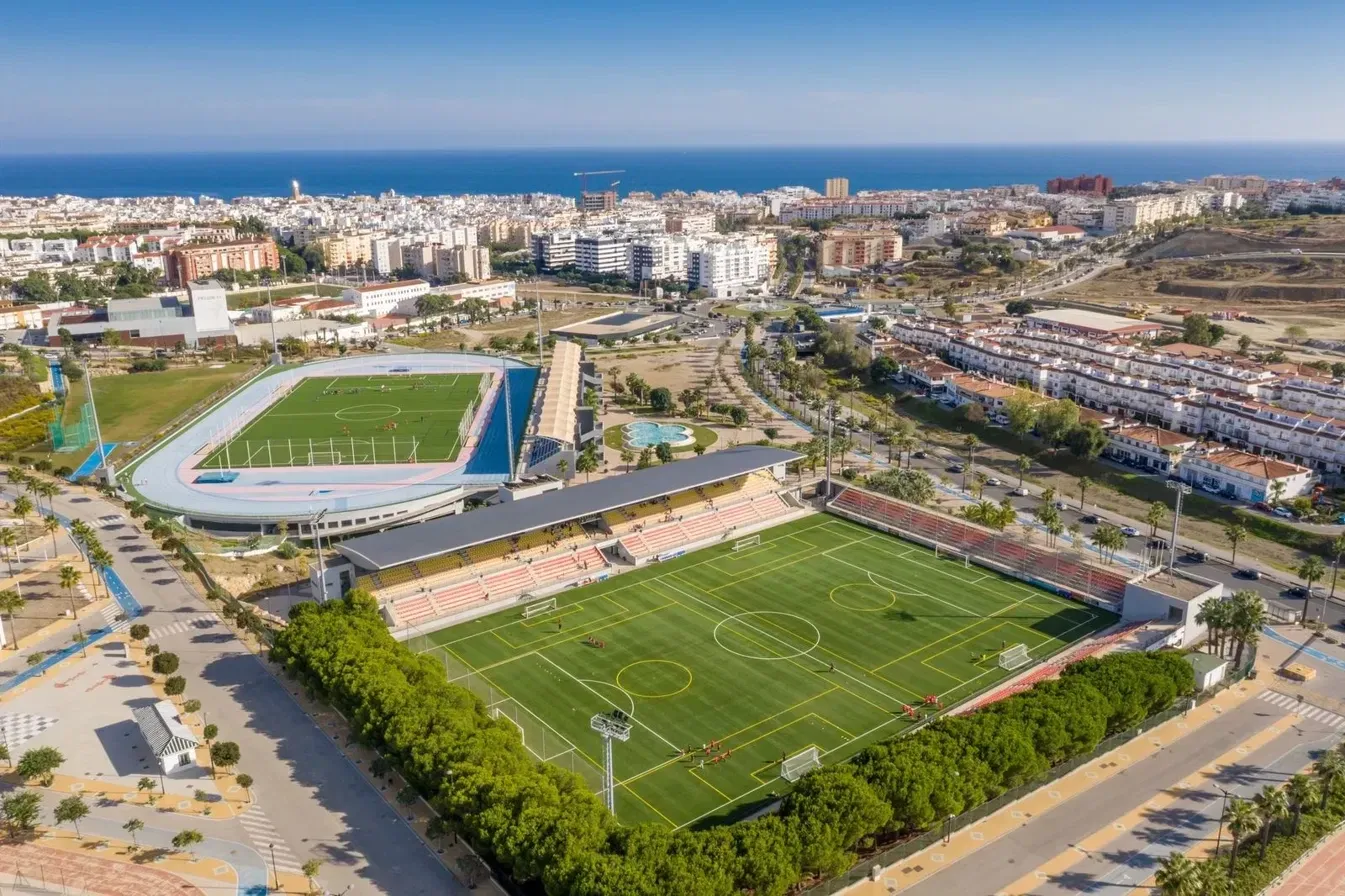 Vista aérea del Estadio Municipal Francisco Muñoz Pérez y del Estadio Municipal de Atletismo de Estepona, con la ciudad y el mar al fondo